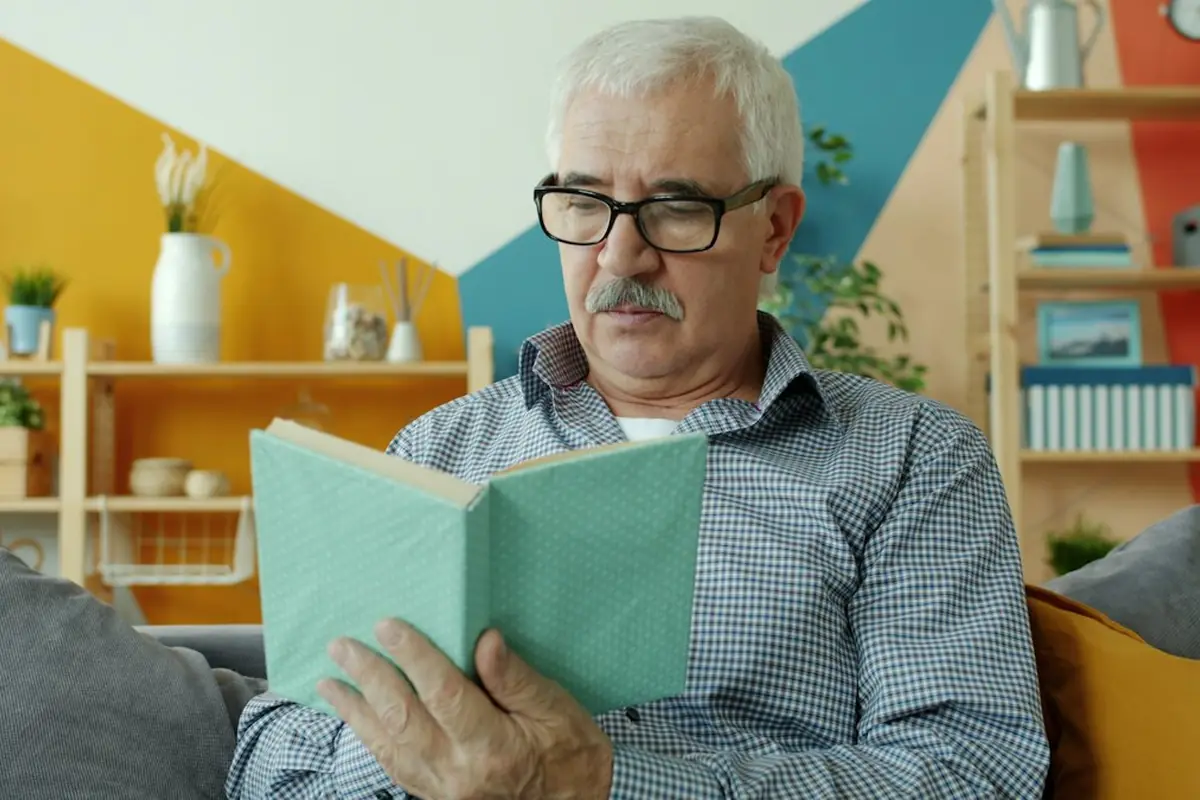 Man wearing reading glasses enjoying a book at home